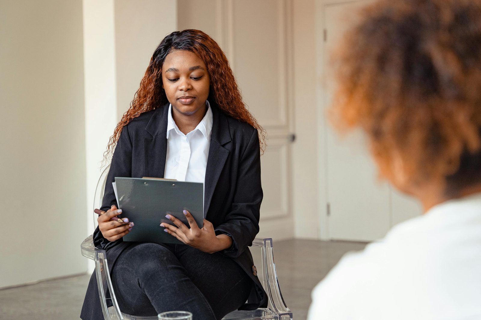 A professional sits with a clipboard during an interview &mdash; thoughtful, considered, present