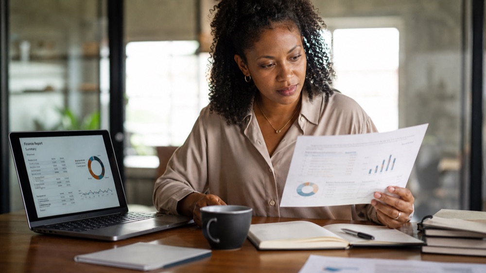 Professional reviewing a report and laptop summary during the AI for Everyday Work course