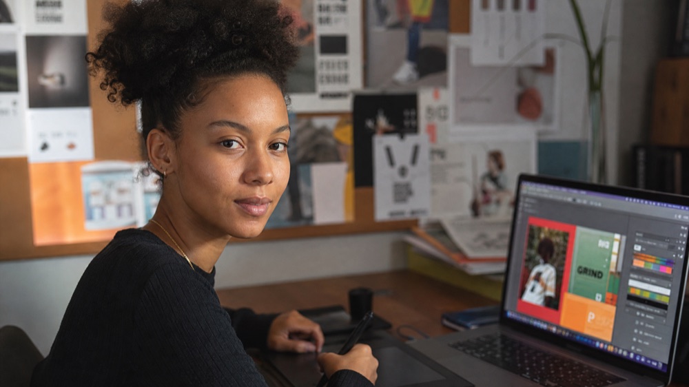 Graphic designer working with AI design tools on a laptop during the AI for Designers workshop