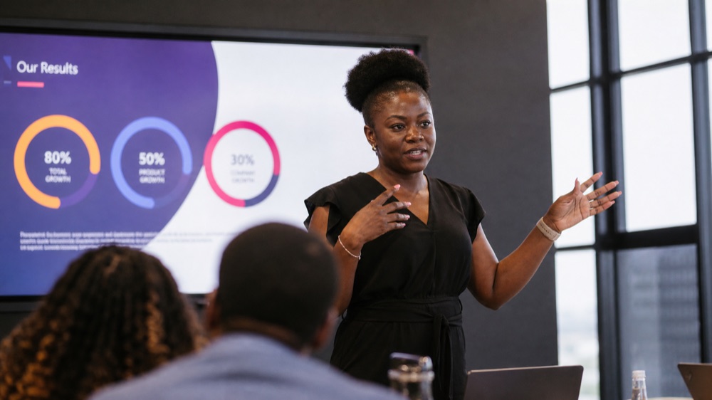 Professional presenting a slide deck with results to a small group during the AI for Presentations workshop