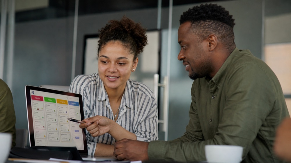 Two professionals reviewing a ClickUp task board during the AI Project Management course