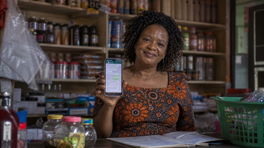 Zimbabwean shop owner using WhatsApp on her phone during the AI for Small Business course